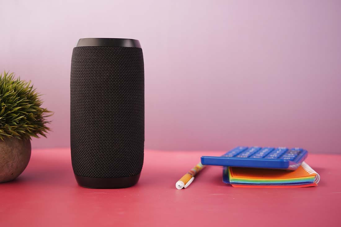 Black portable Bluetooth consumer speaker sitting on a desk next to school supplies