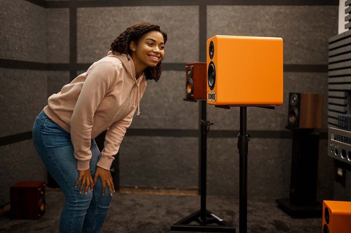Producer listening to active studio monitors elevated on height-adjustable floor speaker stands