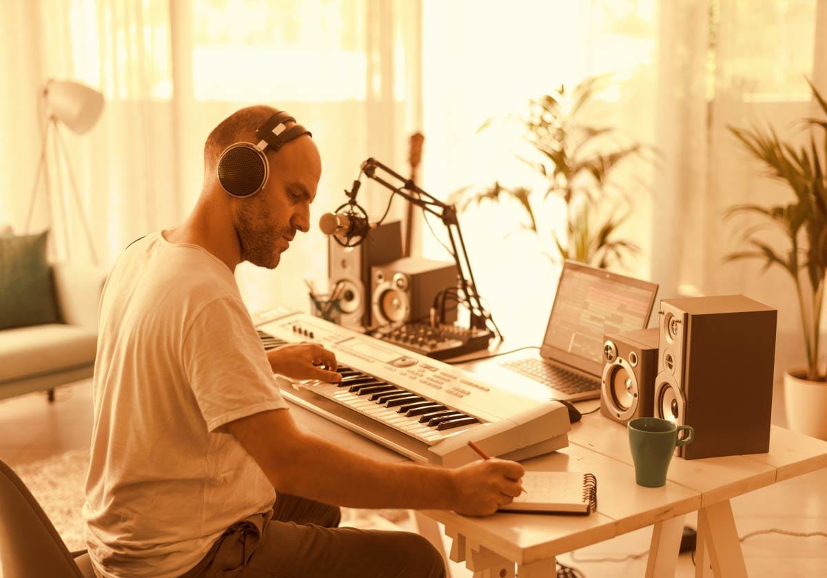 Small room home studio setup featuring a producer working with headphones at a desk.