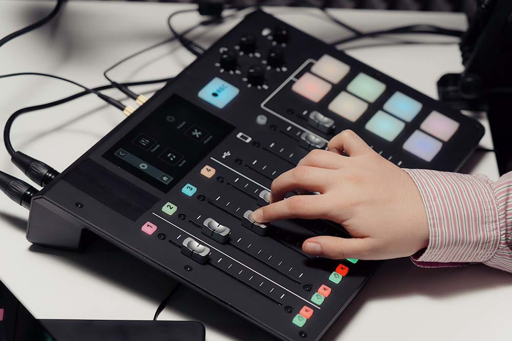 Hand adjusting volume fader on a desktop USB MIDI control surface and mixing console