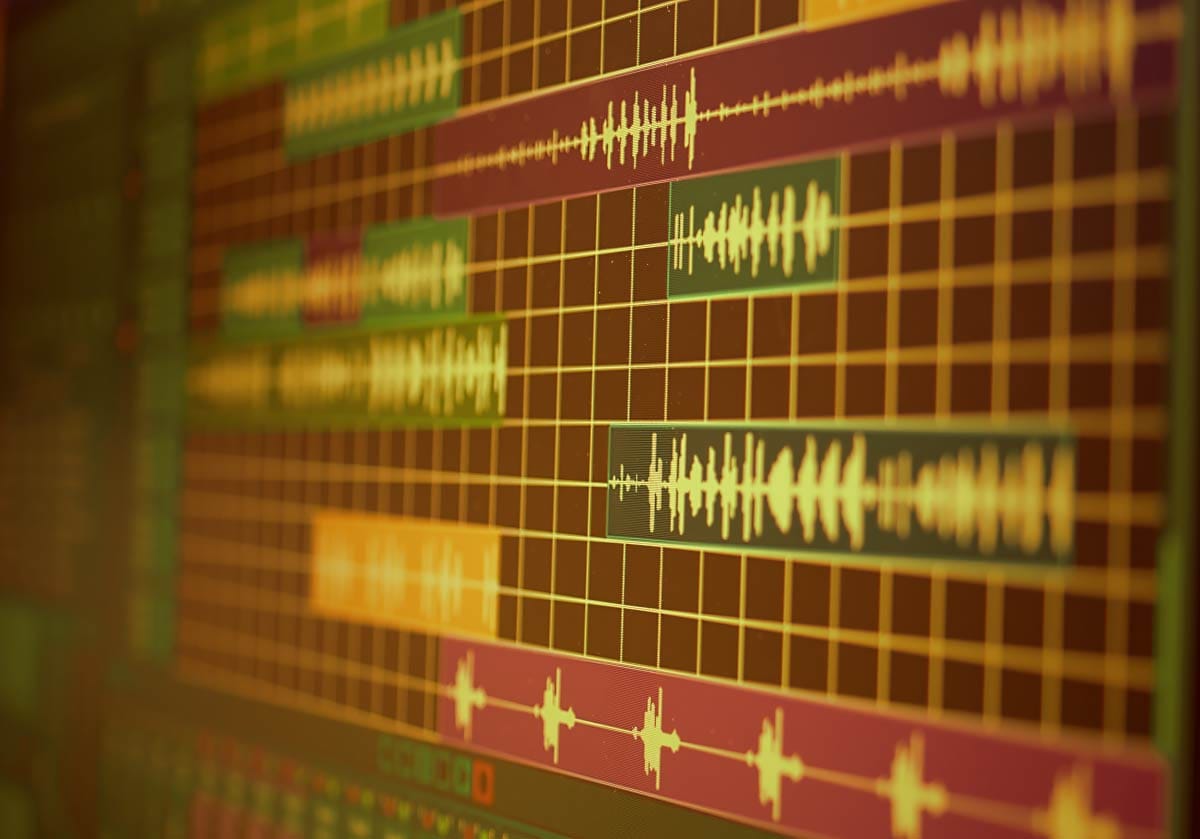 Close-up view of audio waveforms and color-coded tracks inside a DAW session timeline