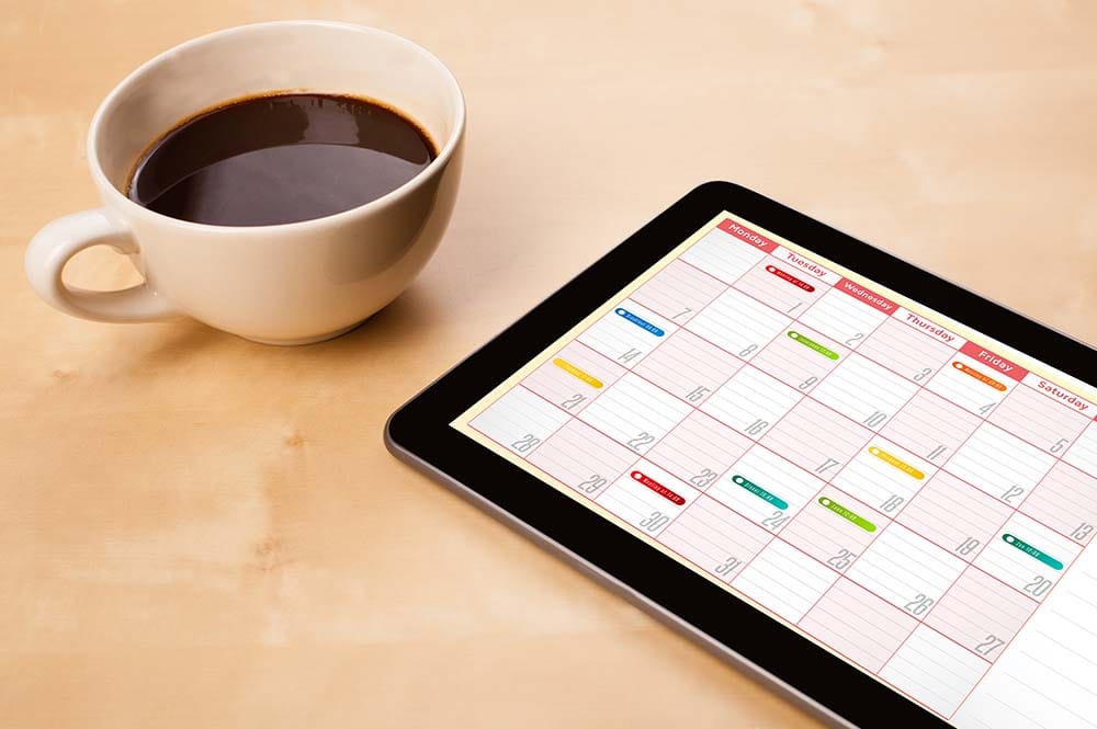 Digital calendar app displayed on a tablet next to a cup of coffee for planning weekly music production practice sessions.