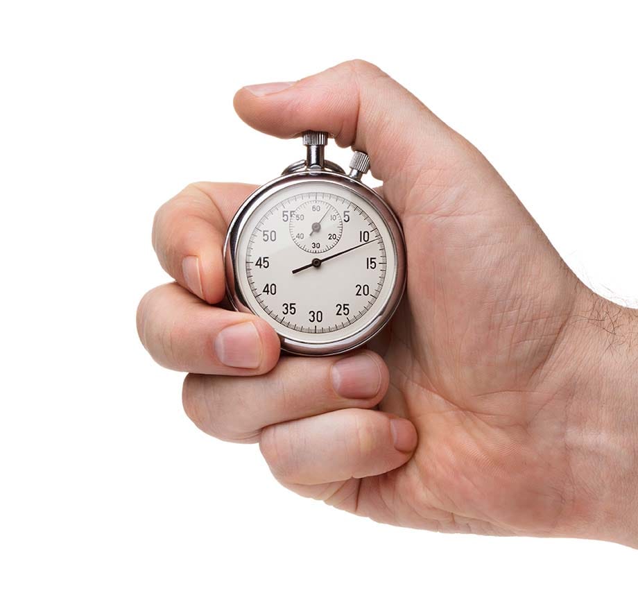 Hand holding a classic analog mechanical stopwatch against a white background for timing music production speed drills.