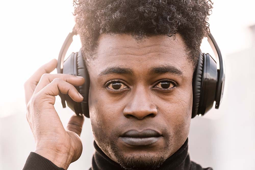 Close-up of a music producer listening intently through over-ear studio headphones while focusing on a song.