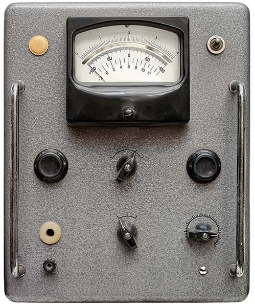 Vintage analog audio control panel featuring a large VU meter and industrial control knobs from the early days of radio broadcasting