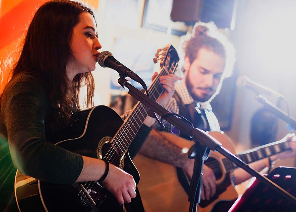 A singer and guitarist recording, representing how similar sounds can frequency mask each other.