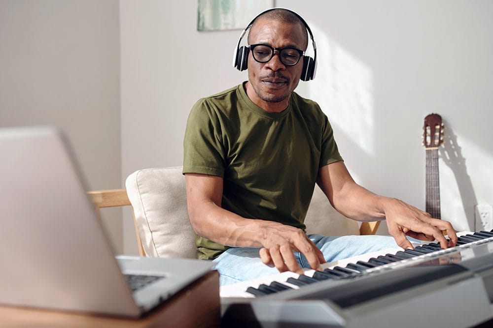 A man composes a song in his home studio representing the kind of music producer that MIDI Madness is made for.