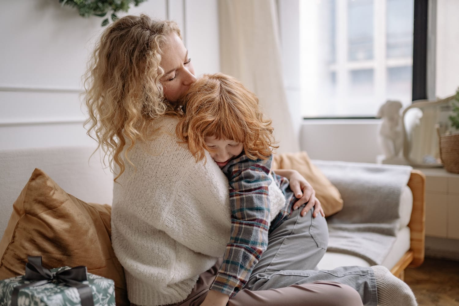 A mother embracing her child on the couch, a quiet moment of comfort