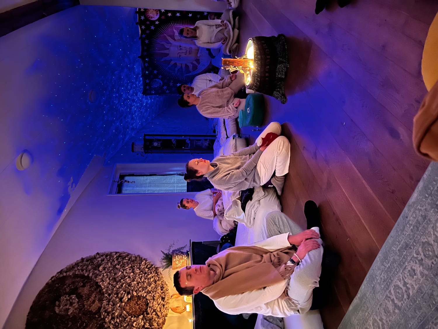 Group meditating together before ceremony, candlelit room