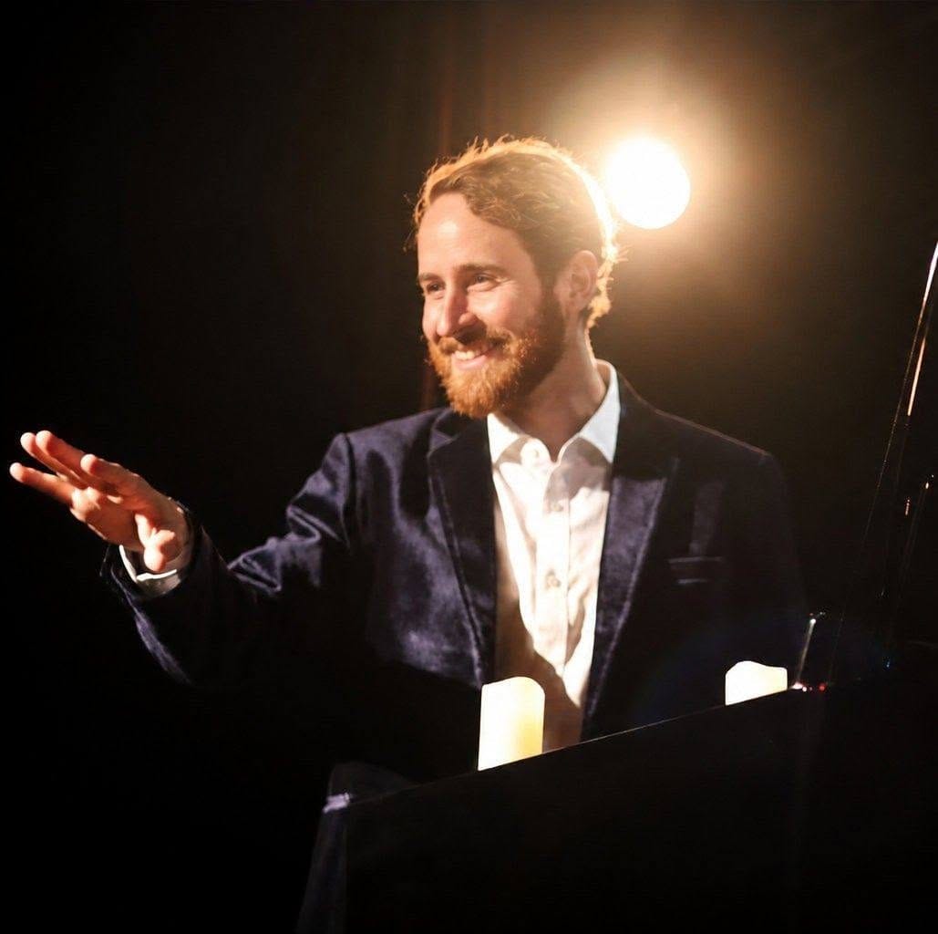 François Verger en concert, en veste bleue, éclairé par un projecteur