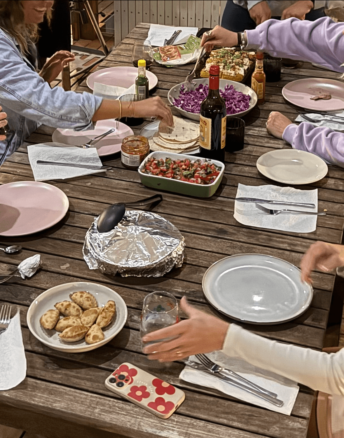A phone sitting on a dinner table alongside plates and glasses