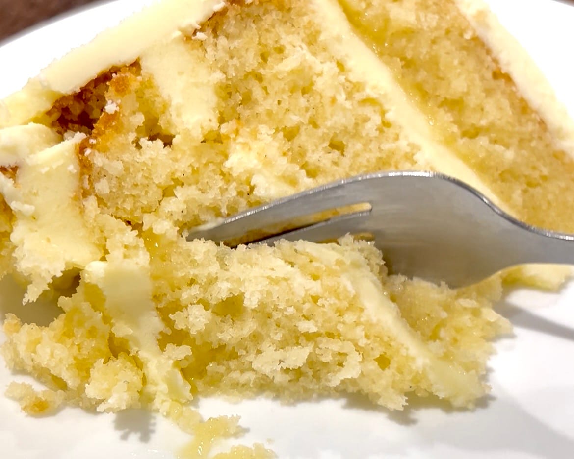 Hands gently pulling apart a vanilla cake cupcake to reveal its moist, fluffy crumb