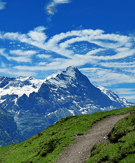 Im Hintergrund die Eiger-Nordwand im Berner Oberland mit einem Wanderweg im Vordergrund. Am Himmel sind bizarre Wolkenformationen die aussehen wie eine liegende 8.