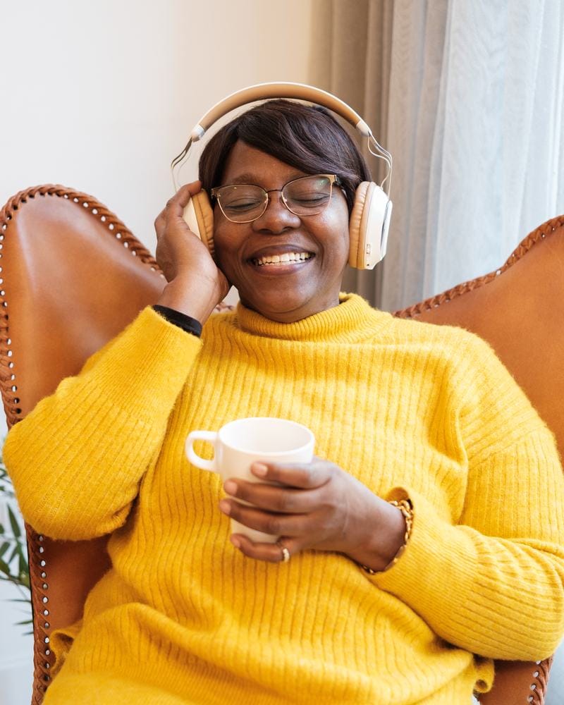 Woman in a yellow sweater smiling with her eyes closed