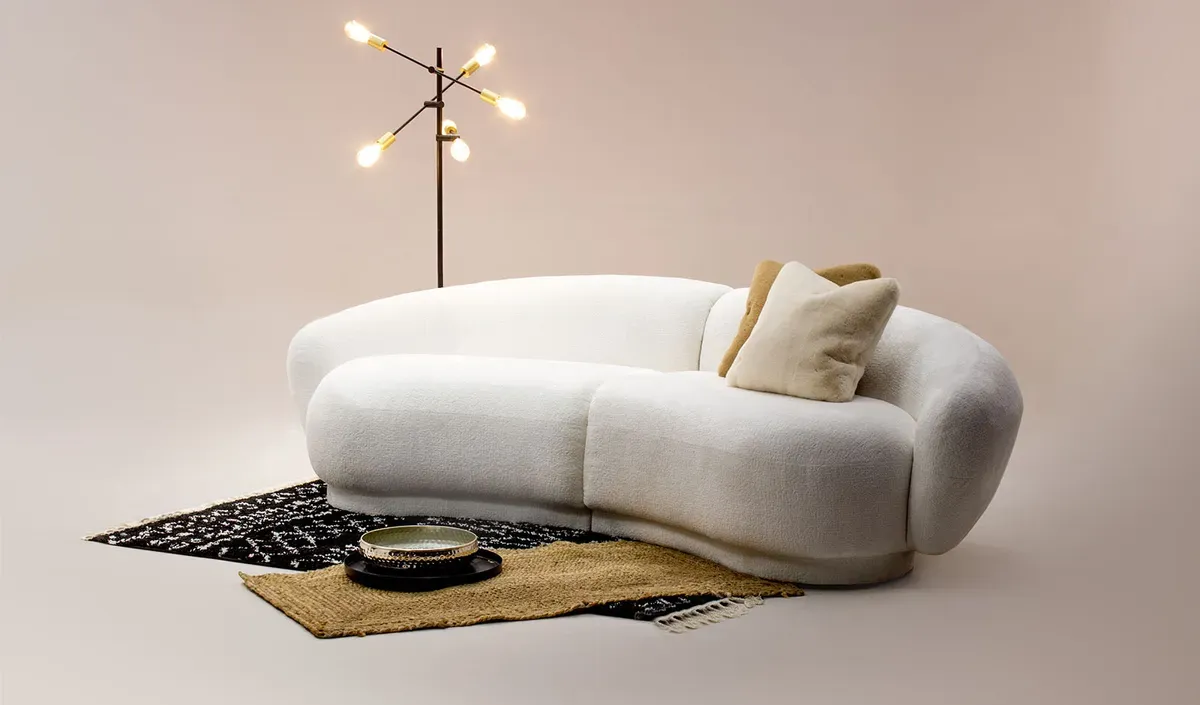 Canapé design en tissu bouclé blanc aux lignes courbes et confortables pour un salon minimaliste.