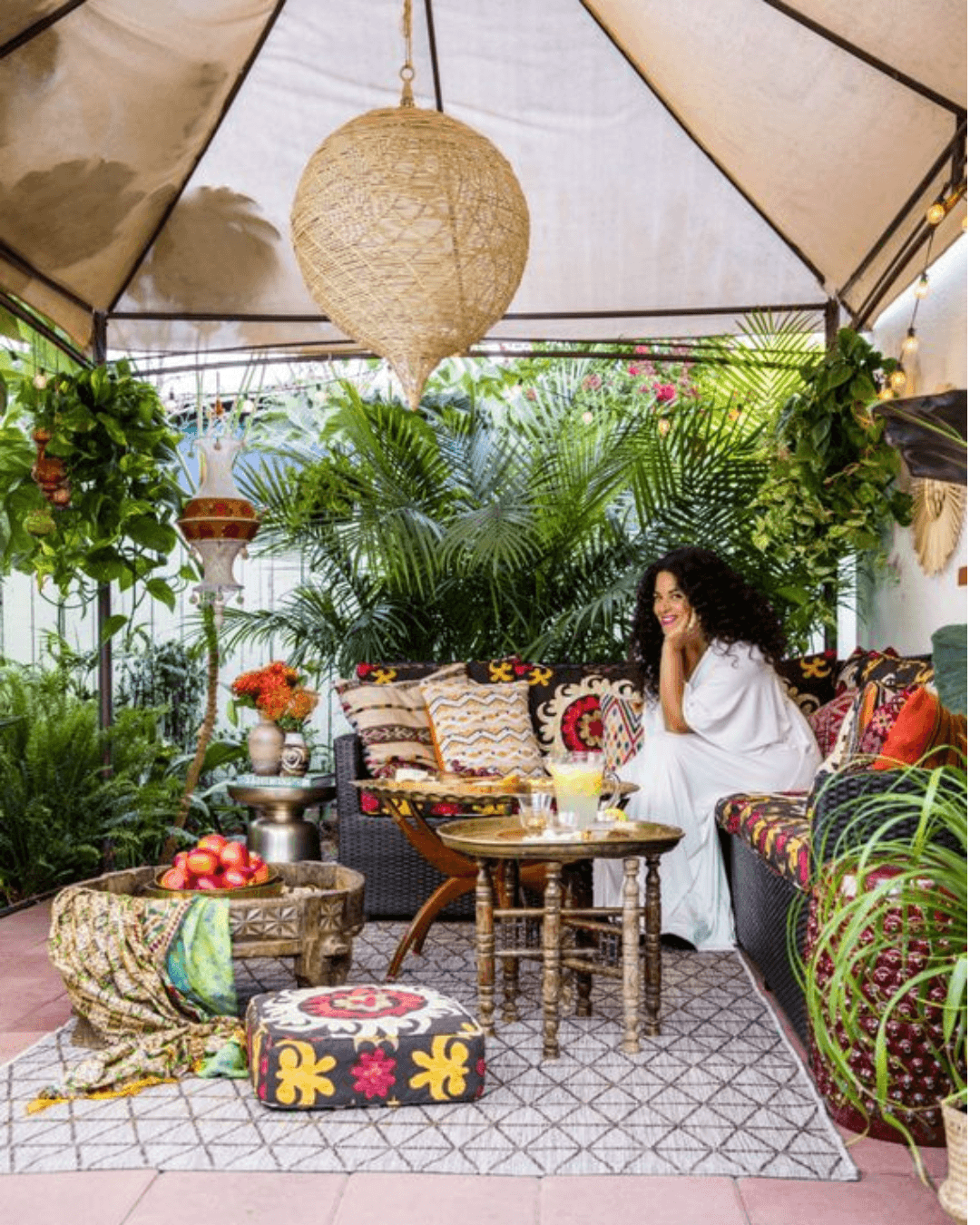 Patio extérieur bohème tropical avec hamac en macramé, plantes exotiques et lanternes solaires.