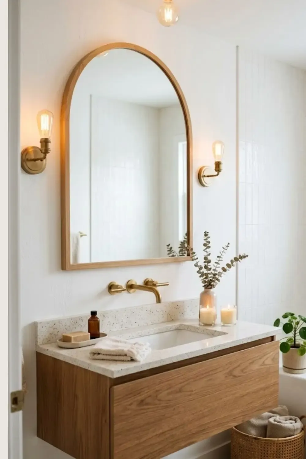 Ambiance zen dans une salle de bain aux tons neutres, incluant des paniers en osier sous le lavabo, une robinetterie en laiton brossé et des accessoires en céramique artisanale.