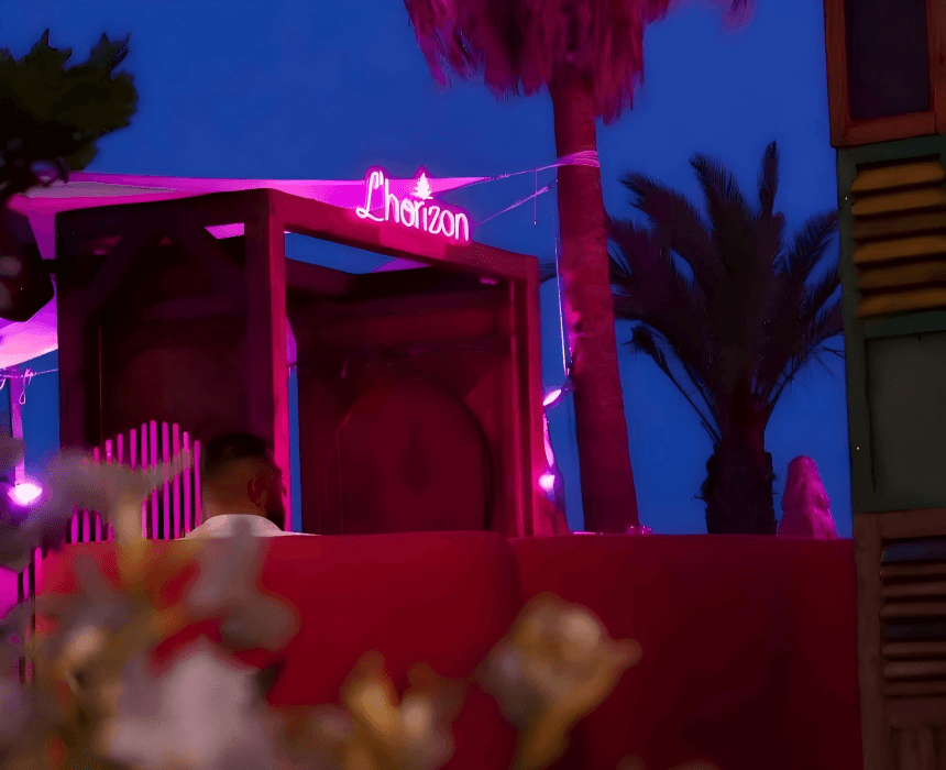 ambiance nocturne restaurant L'Horizon Cap d'Agde / cabanas éclairage néon rose et palmiers / paillote Hérault vue de nuit