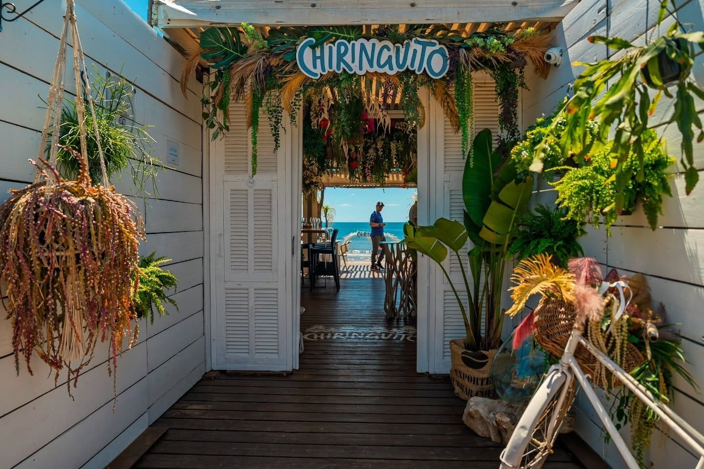 entrée paillote bohème chic Chiringuito Vias-Plage / volets blancs et plantes suspendues / restaurant de plage Hérault vue mer