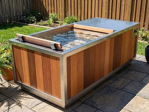 A filled cold plunge tub on a stone patio