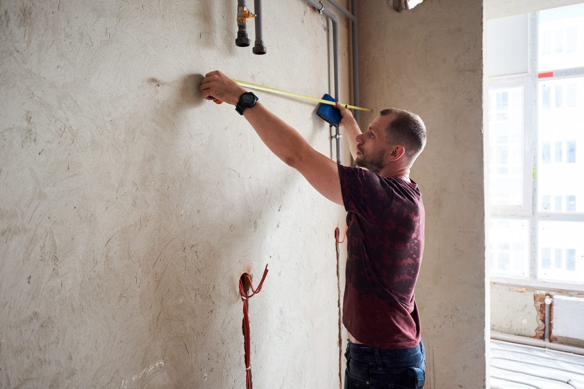 A man measuring a wall with a tape measure