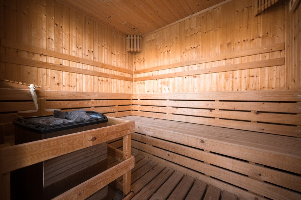 A wooden sauna room with an electric heater and benches