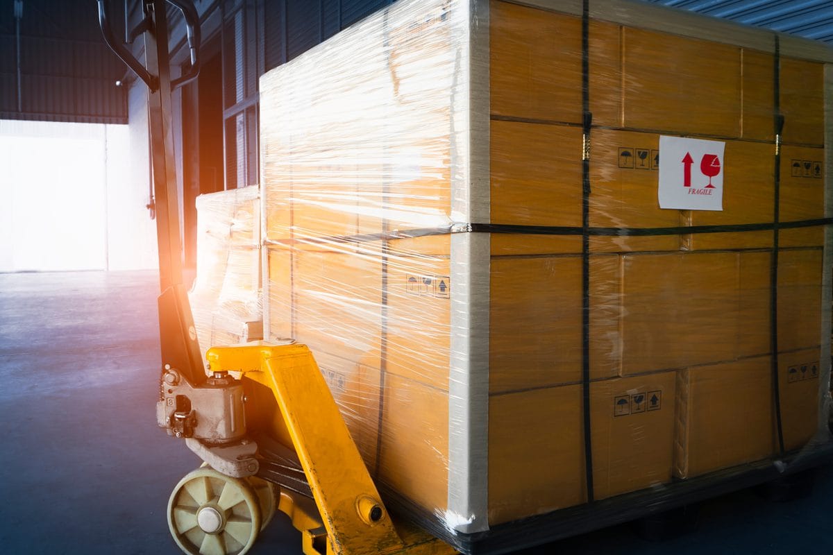 Boxed freight wrapped on pallets beside a pallet truck
