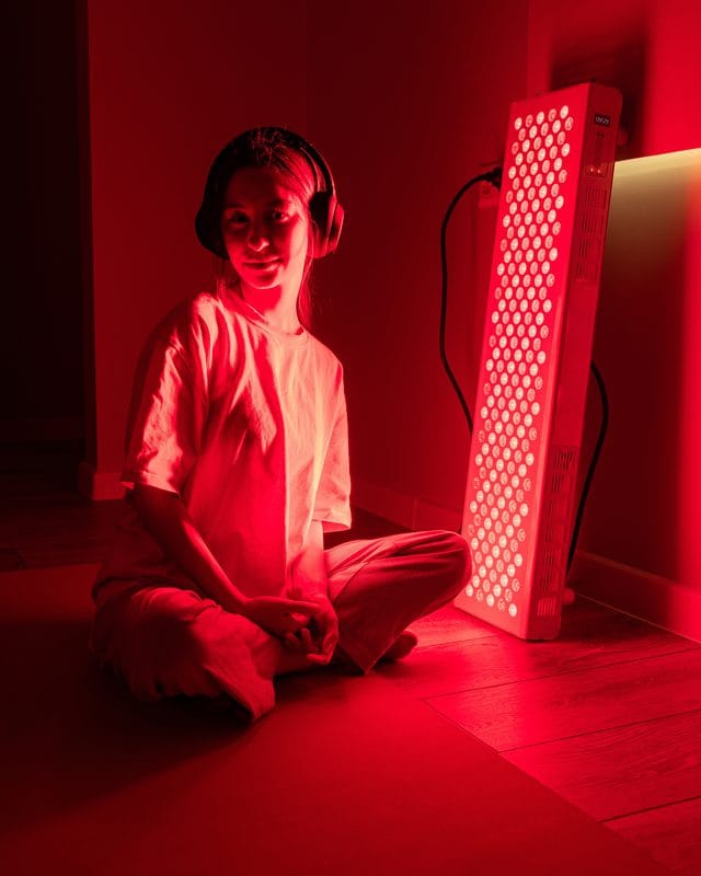 A woman seated in front of a full-length red light panel