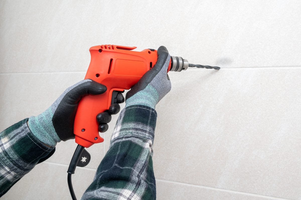 A hand drilling into a wall with a power drill
