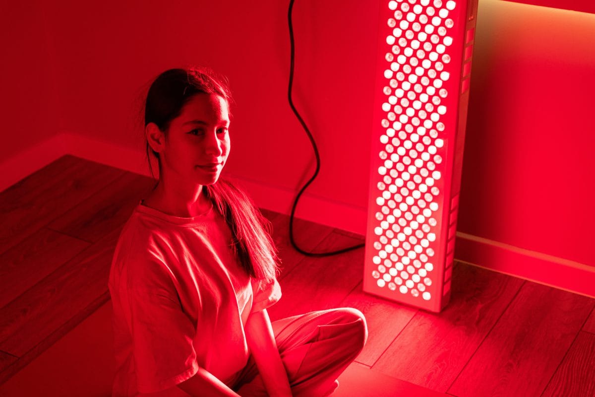 A woman sitting on the floor beside a tall red light panel