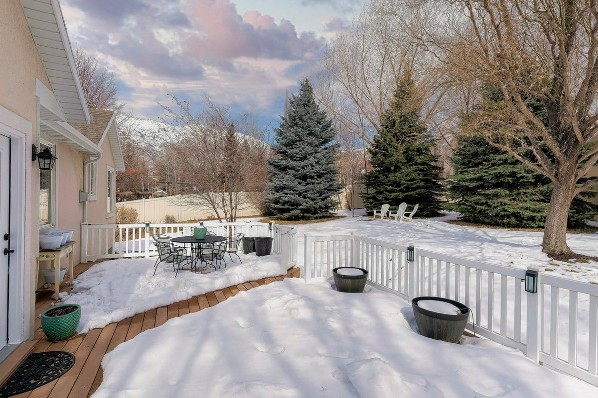 A snow-covered backyard deck beside a house