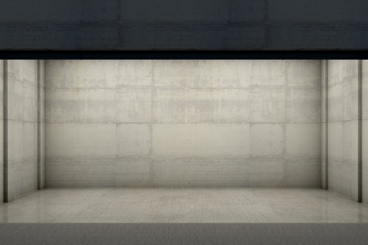 An empty concrete room with a wide open front, seen from outside