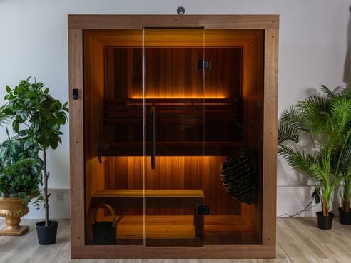 An indoor cedar sauna cabin with a glass front