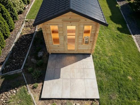 Aerial view of a small cabin sauna and its concrete pad in a backyard
