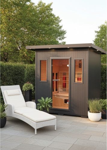 Gray SunRay Pacific 400D6 cabin with a flat overhanging roof and a glass door between two narrow windows, on a stone patio beside a white lounge chair