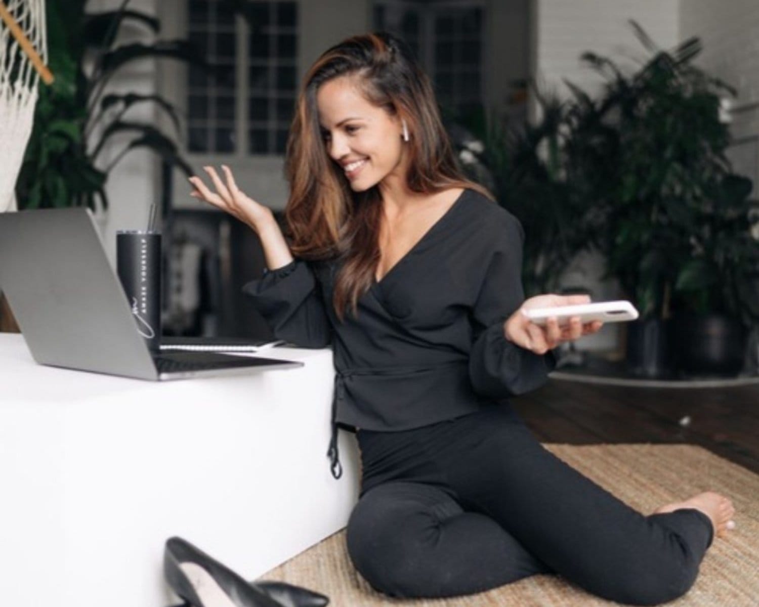 Une femme souriante assise au sol devant son ordinateur, le RESET d'Em Coaching