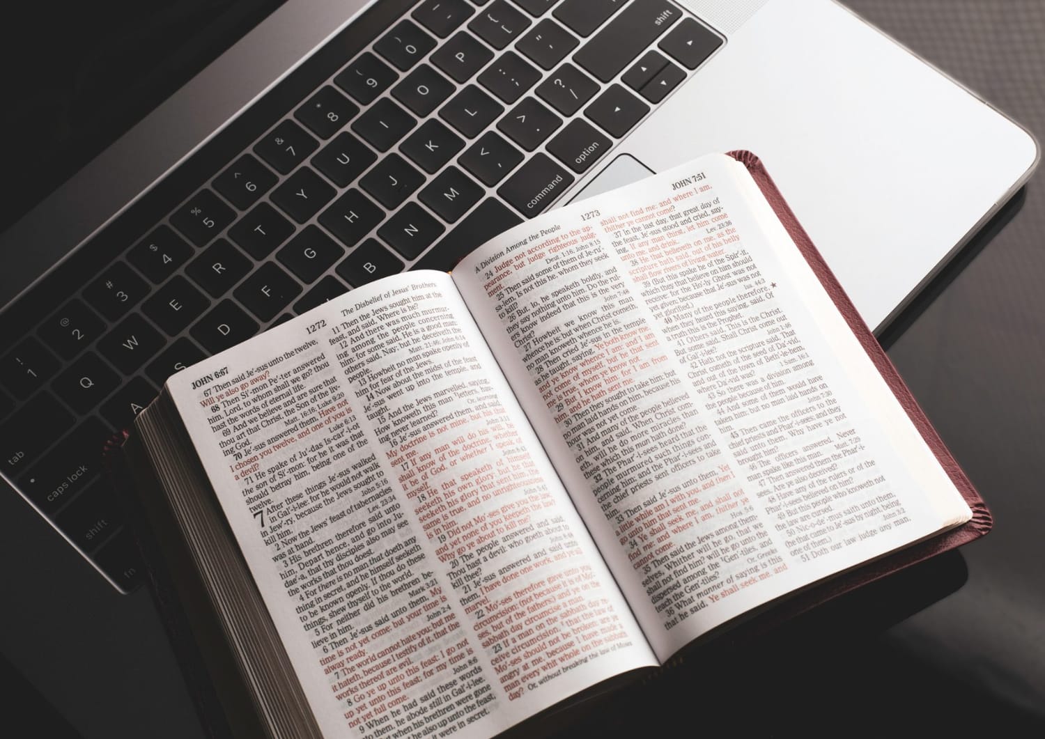 An open Bible resting on a laptop keyboard