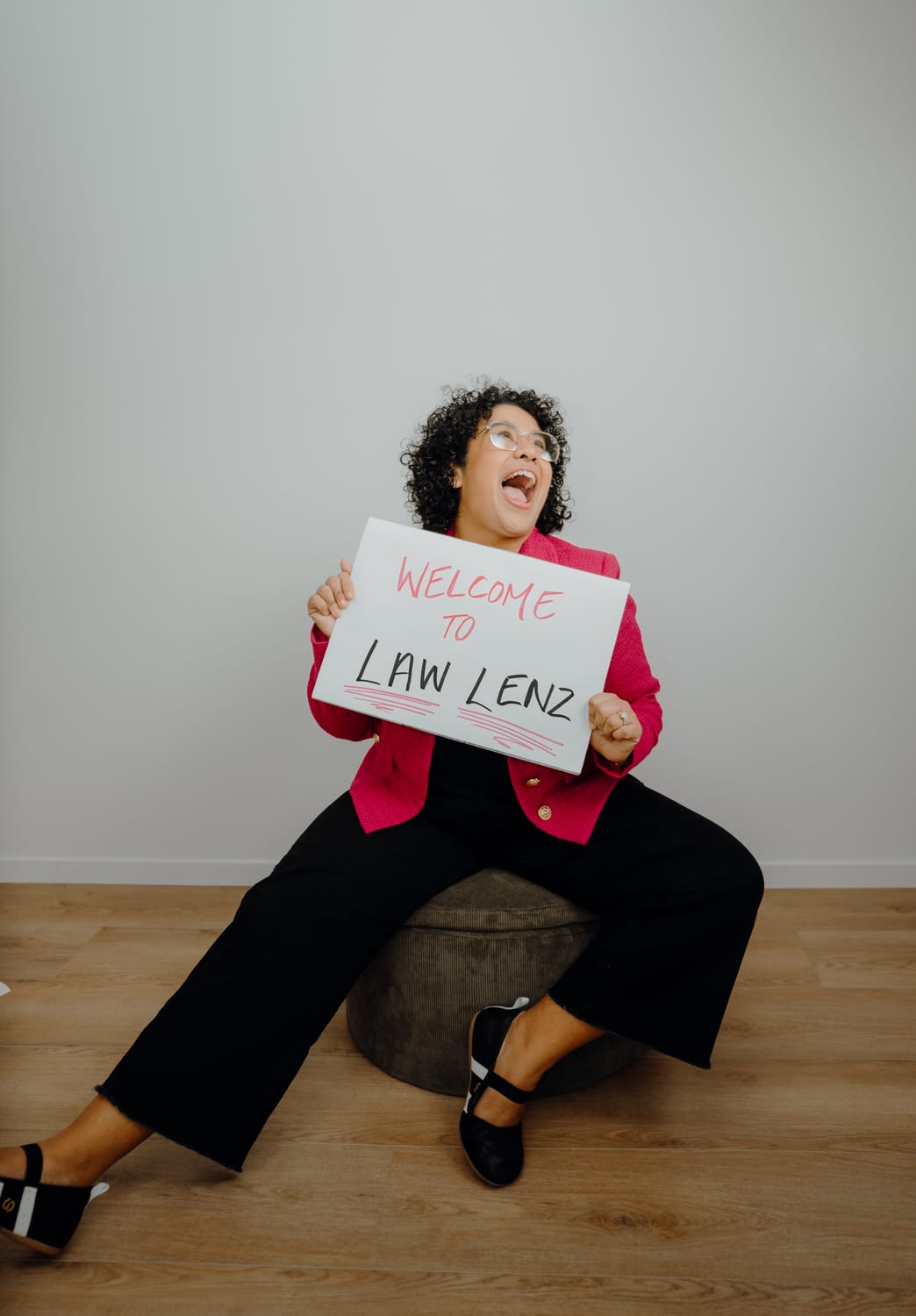 Sanam Permal, employment lawyer and founder of Law Lenz, holding a Welcome to Law Lenz sign