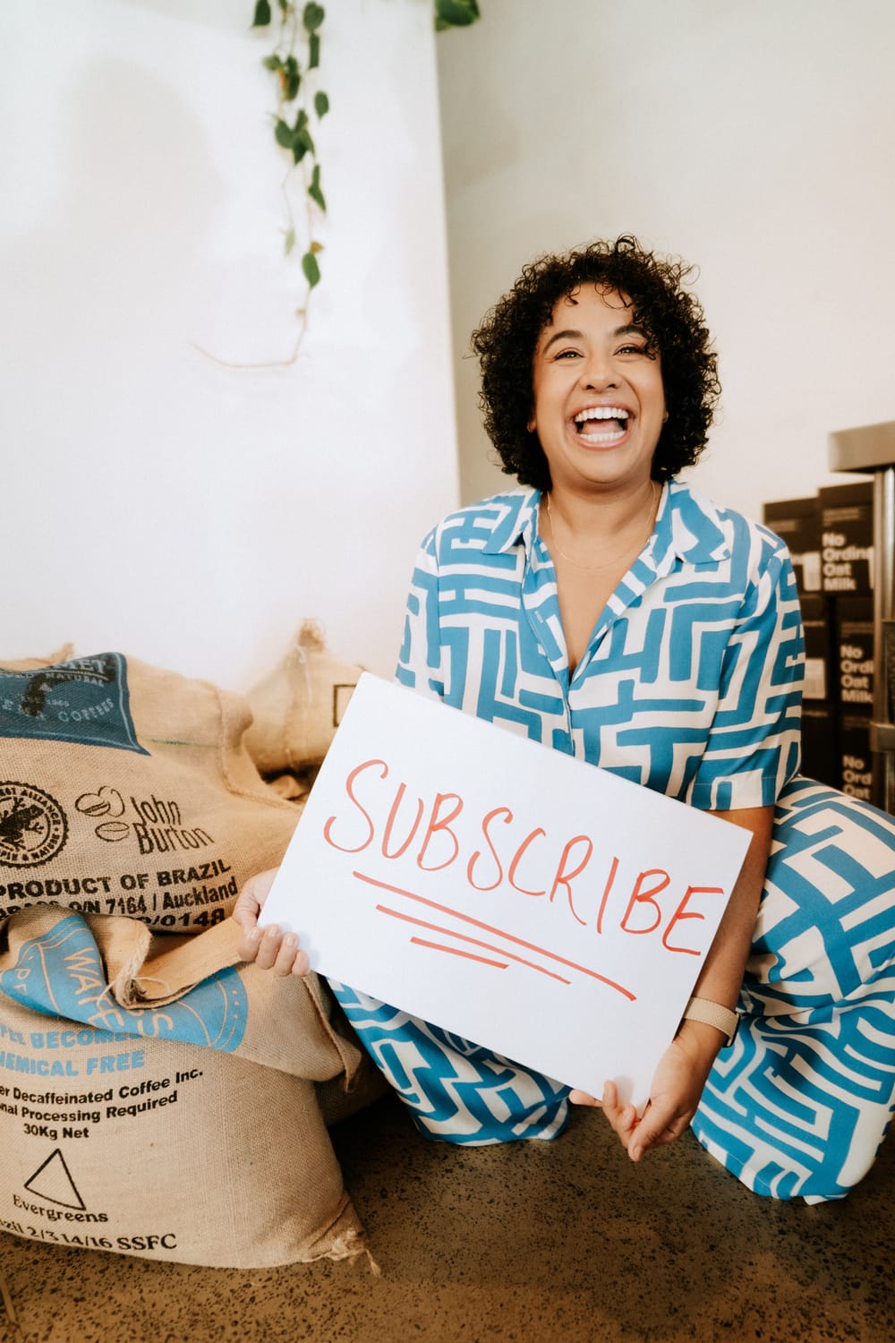 Sanam Permal holding a Subscribe sign