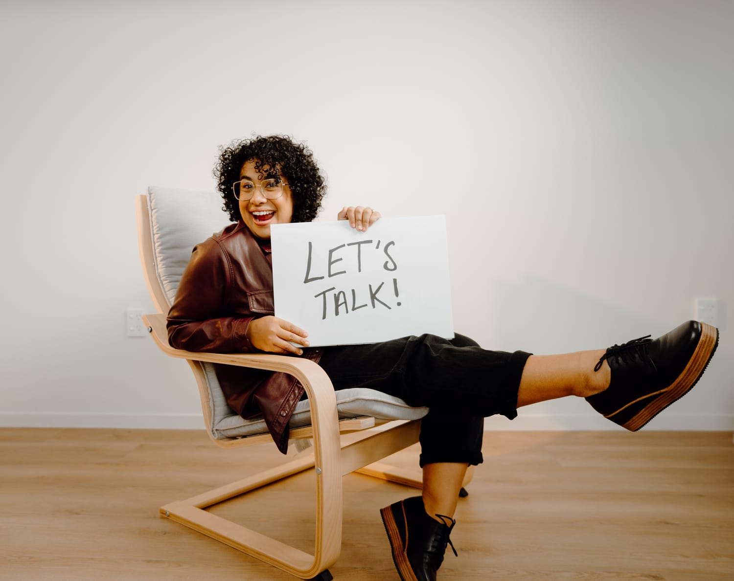 Sanam Permal holding a Let's Talk sign, smiling