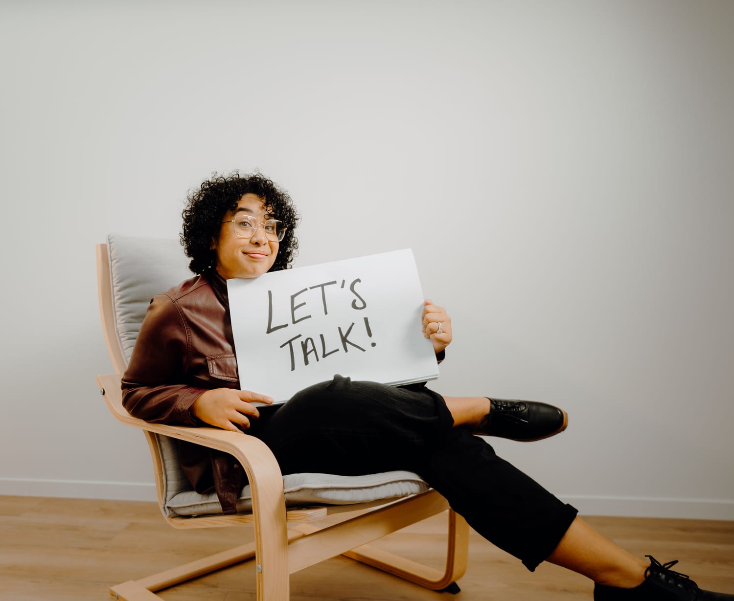 Sanam Permal with a knowing look holding a Let's Talk sign