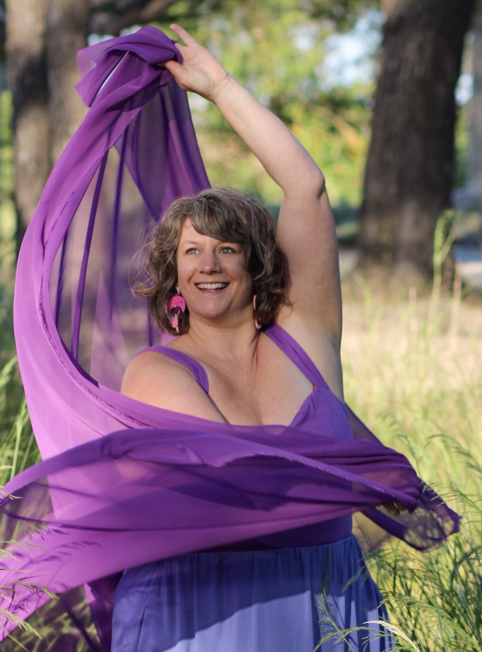 Autre photo de Céline Captin qui danse dans la nature avec un voile violet. Elle est souriante, ses yeux pétillent. Elle est libre, heureuse et pleinement épanouie.