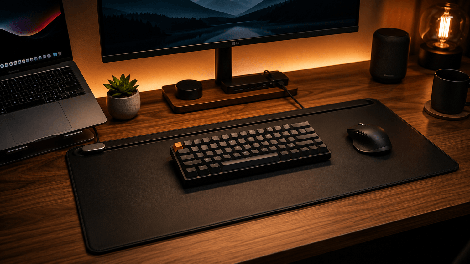 A clean and minimalist home office desk setup featuring a large black premium desk mat with a compact mechanical keyboard and ergonomic wireless mouse neatly arranged on top. The workspace includes warm ambient lighting, a wooden desk surface, a laptop on a stand, a widescreen monitor with soft backlighting, organized cable management, and modern desk accessories like a small plant and coffee mug. The cozy creator-style setup has cinematic shadows, a premium productivity aesthetic, and a clutter-free work-from-home atmosphere.