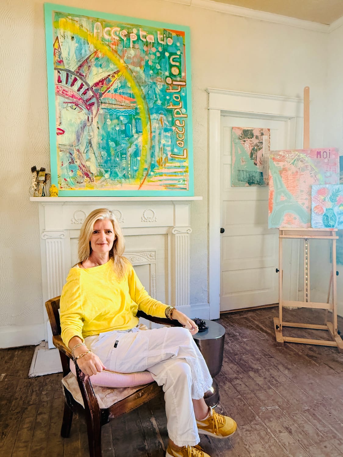 Sandrine Daubord seated in her studio beneath her painting Acceptance