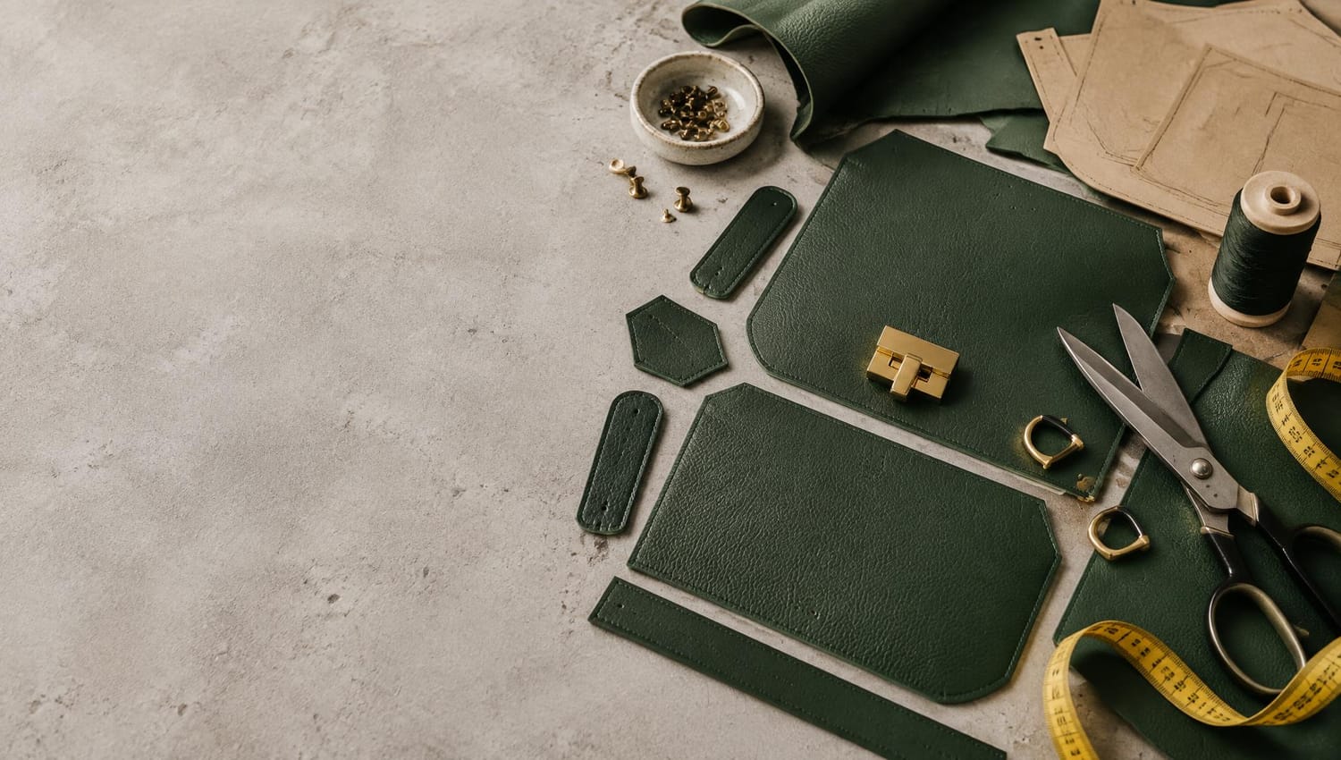 Leather panels, pattern pieces and bag-making tools on a workshop table