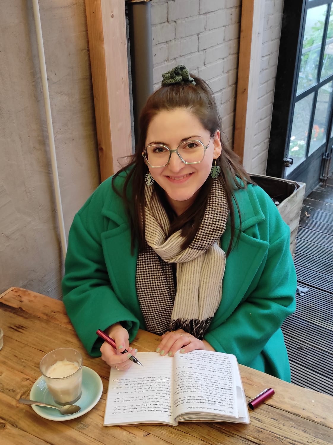 Barbara Nick-Labatzki - Sensitivity Readerin und Dozentin für kreatives Schreiben sitzt mit Kaffee und Notizbuch am Tisch.