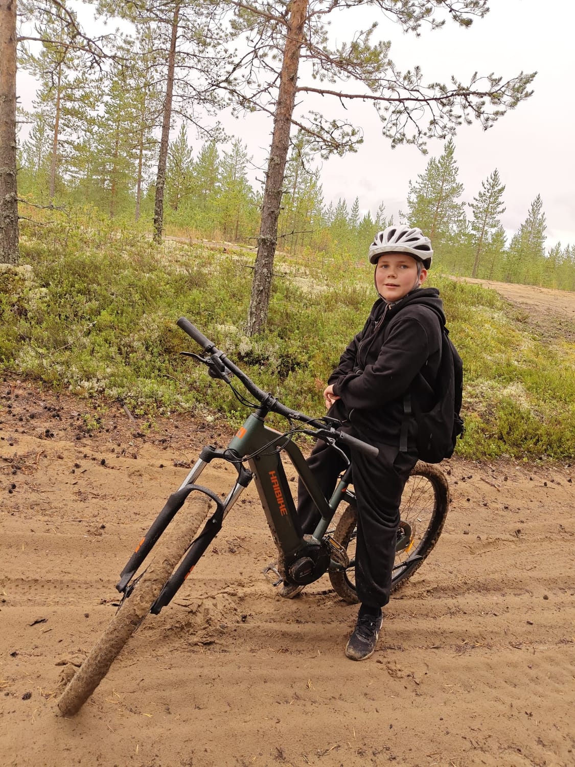 Nuori sähköpyörän kanssa metsätiellä.
