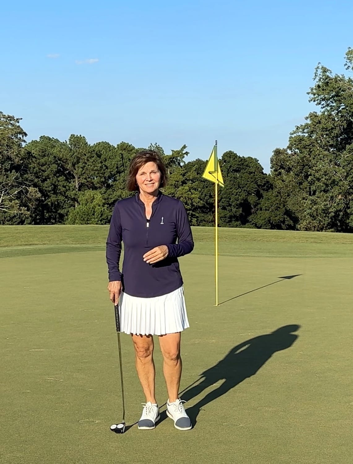 Coach Kathy Hart standing on the green with a putter