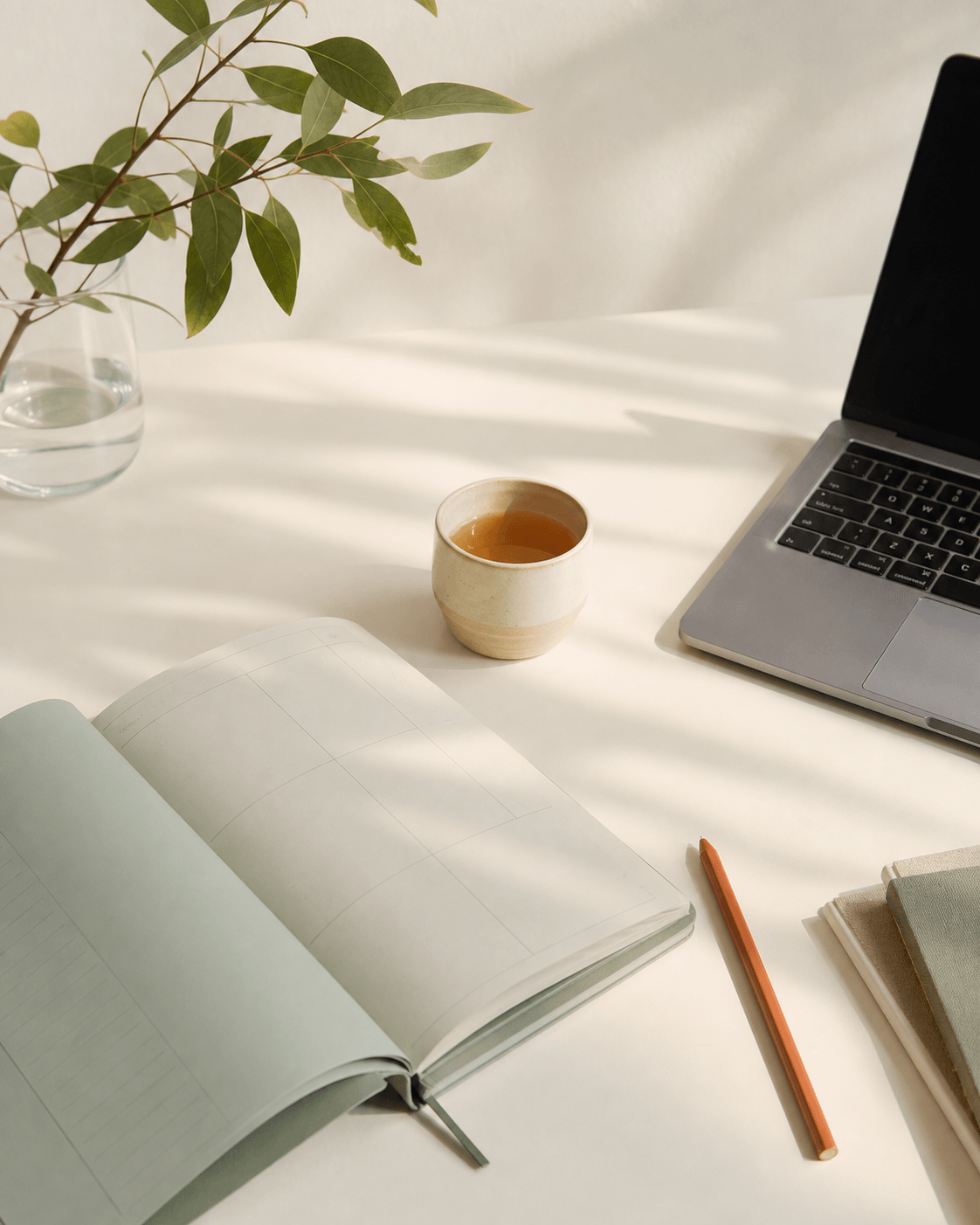 Carnet de planification ouvert, tasse de thé et ordinateur sur un bureau lumineux