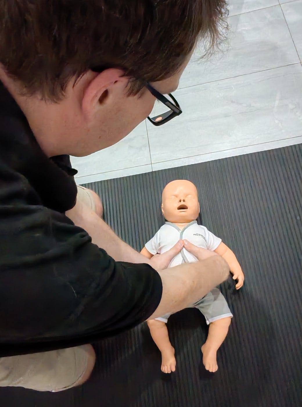 James demonstrating chest compressions on an infant training manikin